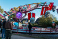Besucher auf der Hünxer Honigkirmes 2026 zwischen Ständen und Fahrgeschäft. Die Personen sind von hinten oder unscharf zu sehen.